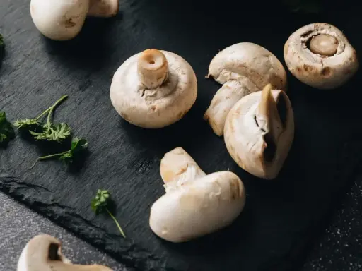 Świeże pieczarki na czarnej desce. Zastanawiasz się, czy pieczarki można mrozić? Tak, można je mrozić, zachowując ich smak i aromat.