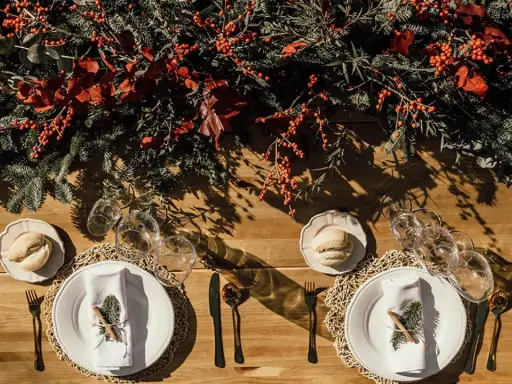 Decoración festiva para una boda en diciembre. Mesa de madera con ramas de pino, bayas rojas y detalles rústicos.