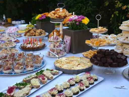 Ein üppiges Brunch Buffet im Freien mit Croissants, Quiche, Brownies, Sandwiches und süßen Leckereien.