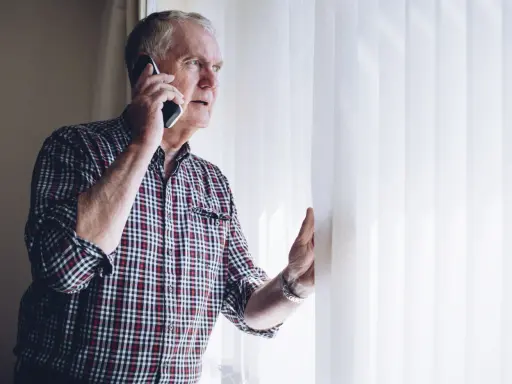Zaniepokojony starszy mężczyzna rozmawia przez telefon, szukając informacji, gdzie zgłosić zaniedbywanie osoby starszej.