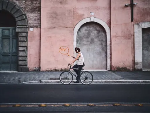 Un ciclista con cuffie ascolta musica mentre pedala, un'istantanea dal reportage di un tour urbano.