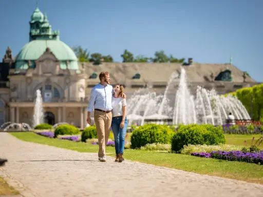 Ein Paar spaziert durch den Kurpark in Bad Oeynhausen. Hier kann man die schönen Brunnen und die Architektur genießen.