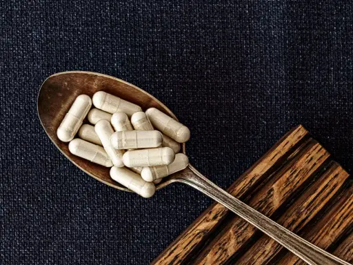 Łyżka pełna kapsułek. Czy to suplementy z glutationem? Co to jest glutation i jak działa?