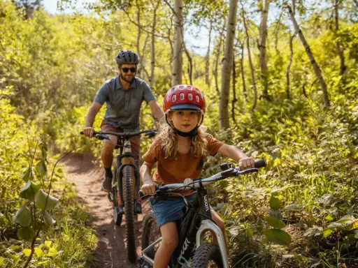 En flicka och en man cyklar på en stig i en lummig skog. Solen lyser genom träden och skapar ett vackert ljusspel.
