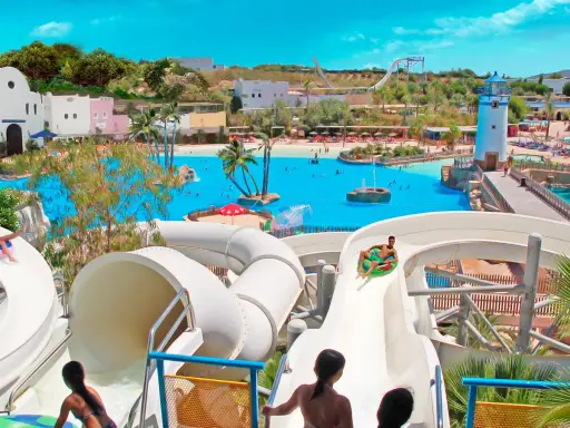 ¡Diversión en el parque acuático Cantabria! Niños disfrutan toboganes y piscina de olas bajo el sol.
