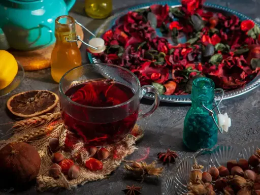 Ein Glas roter Tee, Zitrone und Nüsse. Welcher Tee senkt Cholesterin und Blutdruck? Vielleicht dieser aromatische Aufguss.