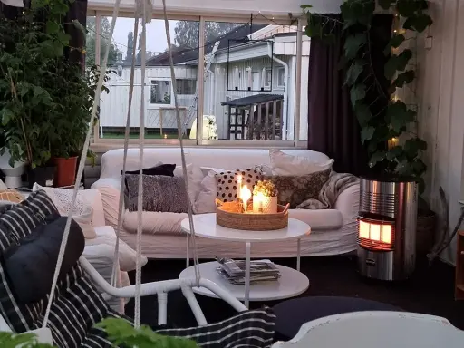 Mysigt uterum med soffa, korgstol och värmare. Perfekt för att inreda uterum för avkoppling.