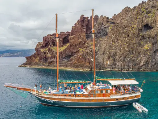Segelschiff mit vielen Passagieren vor steiler Felsküste, ein Traum für Madeira Segeln.