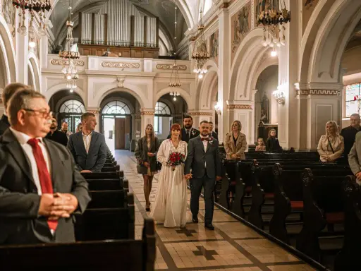 Para młoda idzie do ołtarza przy akompaniamencie piosenki na wejście. W kościele zgromadzeni goście.