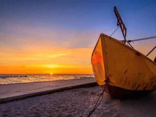 Żółta łódź na plaży w Niechorzu podczas zachodu słońca. Piękne niechorze atrakcje nad morzem.