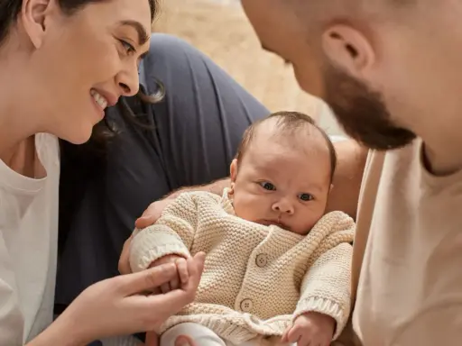 Una madre sonríe a su bebé, mientras el padre lo abraza. A pesar de que mi bebé no tiene apego conmigo, la familia se ve unida.