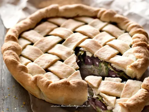 Pizza di scarola con un intreccio dorato di pasta, ripiena di verdure e olive. Un sapore autentico.