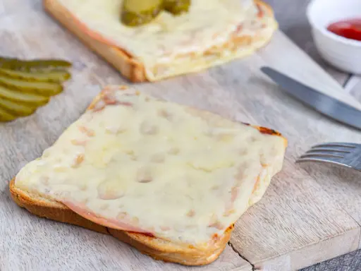 Zwei überbackene Scheiben Brot mit Schinken und Käse, dazu Gewürzgurken. Eine Karlsbader Schnitte, perfekt für den kleinen Hunger.