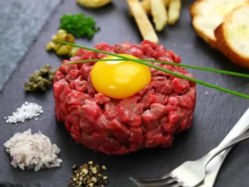 Tatarska wołowina z żółtkiem, kaparami, cebulką i grzankami. Czy można mrozić wołowinę na tatara? Lepiej nie ryzykować.