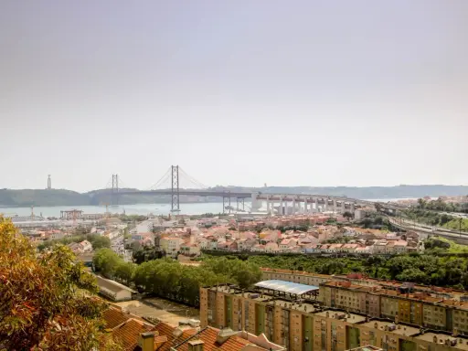 Blick auf Lissabon mit der Hängebrücke und dem Cristo Rei Denkmal. Im Vordergrund die Dächer von Häusern, die an den "Cemitério dos Prazeres" erinnern.