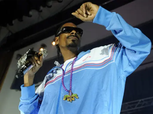 Snoop Dogg w błękitnej bluzie z naszyjnikiem, trzymający mikrofon. Ile pali? Tego nie wiemy, ale na pewno daje czadu na scenie!
