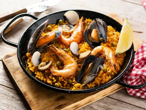Pyszna paella z owocami morza, idealna do przygotowania z ryżem bomba. Krewetki, małże i cytryna dopełniają danie.