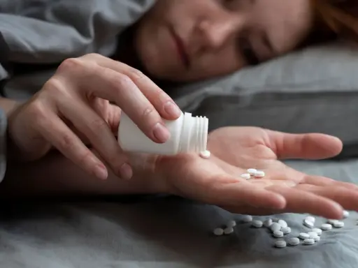 Eine Person nimmt Amitriptylin zum Schlafen ein. Mehrere weiße Pillen liegen auf der Handfläche.