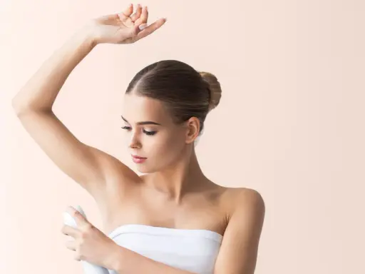 Donna applica deodorante sotto l'ascella. Si discute se l'aluminum chlorohydrate fa male.