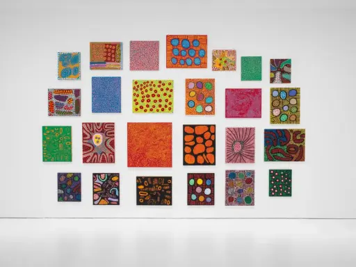 A vibrant collection of paintings by top visual artists, featuring bold colors and abstract patterns, adorns a white gallery wall.