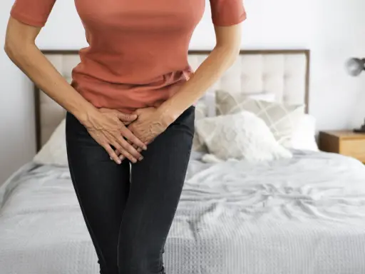 Mujer con las manos en el abdomen, sintiendo dolor de ovarios antes de la regla.