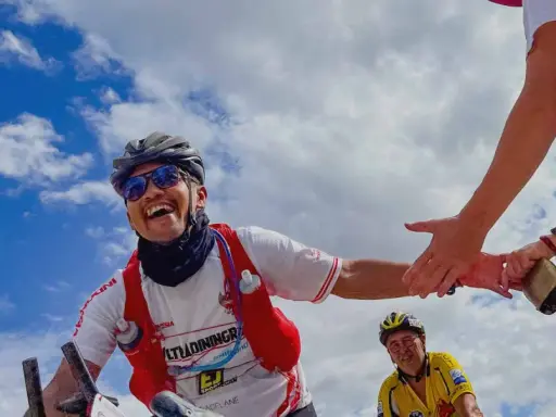 Glücklicher Radfahrer gibt High-Five während Paris Brest Paris. Ein weiterer Radfahrer im Hintergrund.