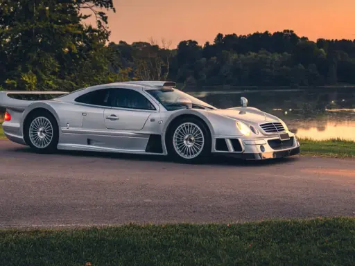 Silberner Mercedes CLK GTR am Seeufer bei Sonnenuntergang. Ein Blick auf dieses seltene Sammlerstück, das den Begriff "Mercedes CLK GTR Preis" neu definiert.