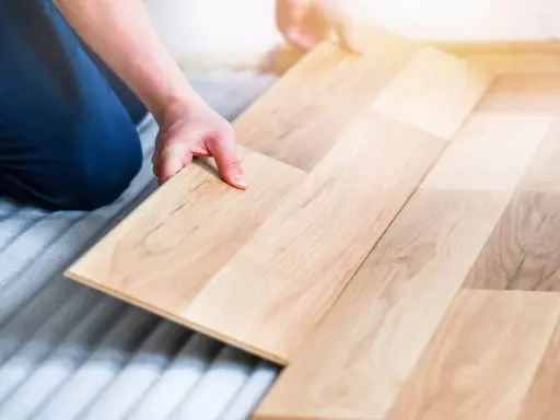 Man colocando una tabla de madera para poner suelo de tarima flotante.