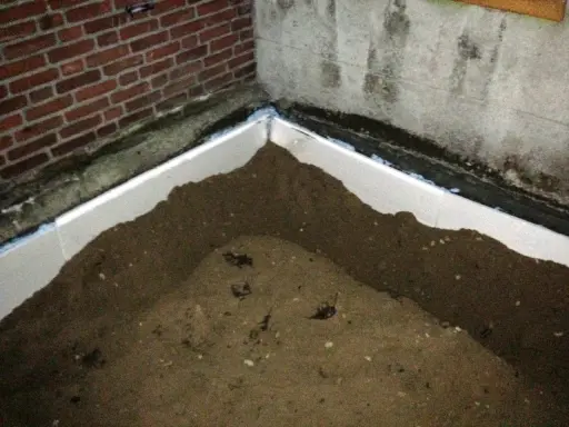Styrodurplatten werden auf Bitumen geklebt, um eine Dämmung zu schaffen. Sand liegt auf den Platten.
