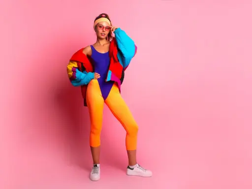 Kobieta w neonowym stroju kąpielowym, pomarańczowych legginsach i kolorowej kurtce, stylizacja inspirowana modą damską lat 90.