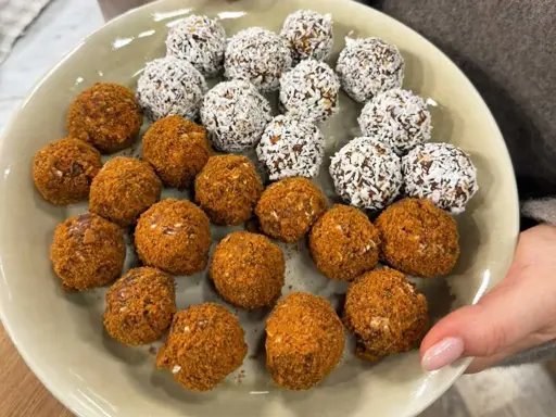 En tallrik med hemgjorda pepparkaksbollar och dadlar, vissa rullade i kokosflingor.