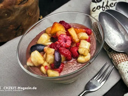 Schokoladige smoothie bowl mit frischen Himbeeren, Bananenstücken und Blaubeeren. Ein gesunder Genuss!