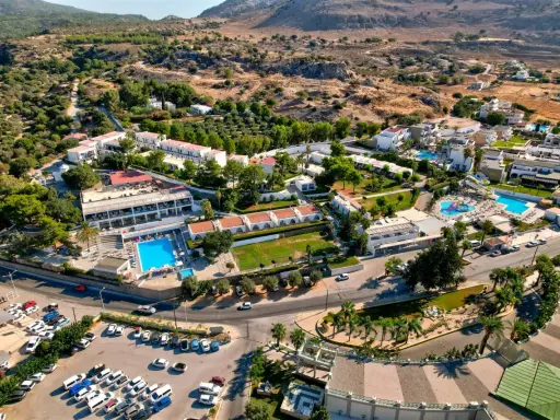 Widok z lotu ptaka na hotel Ellia Rodos z basenami, zjeżdżalniami i parkingiem pełnym samochodów.