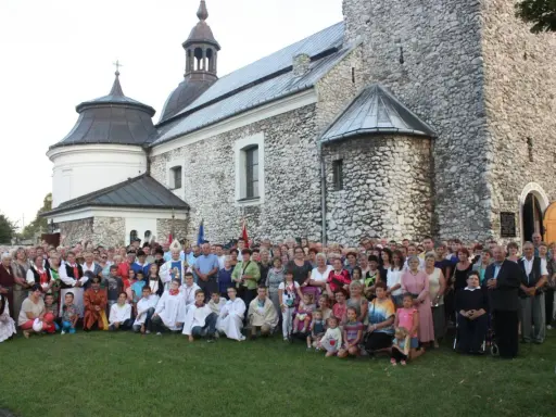 Wielka grupa ludzi, w tym dzieci i duchowni, pozuje przed zabytkowym kościołem parafii Skarżysko.