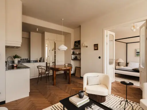 Jak urządzić salon? Jasne, przytulne wnętrze z aneksem kuchennym, jadalnią i sypialnią. Drewniana podłoga w jodełkę, wygodne fotele i stylowe dodatki.