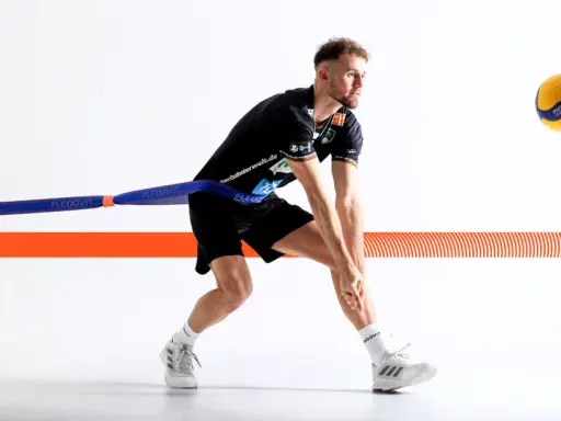Volleyballspieler im Krafttraining mit Widerstandsband, bereit für den Aufschlag.