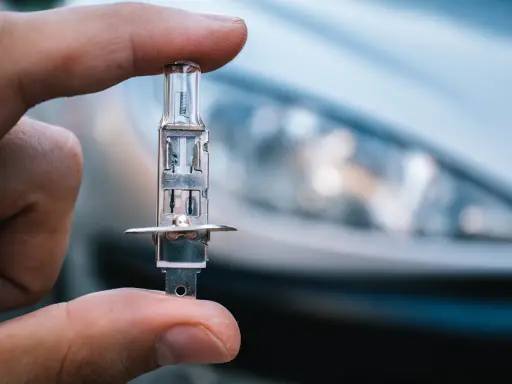 Un dedo sostiene una bombilla de coche, lista para iluminar el camino con sus luces largas.