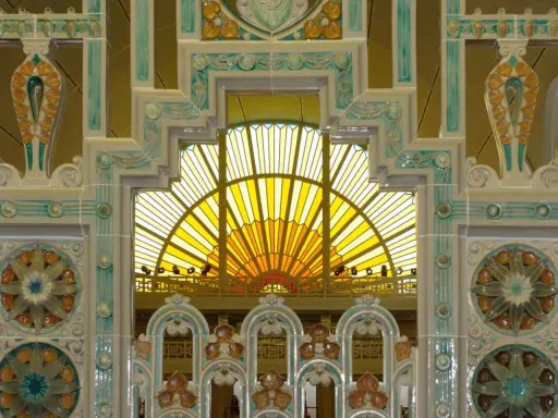 Détails ornementaux en céramique, style art déco, encadrant une verrière jaune rayonnante.