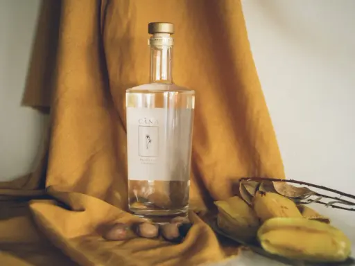 Butelka Cachaça Cãna, brazylijskiego alkoholu z trzciny cukrowej, otoczona owocami i suchymi liśćmi. Cachaca co to? To brazylijski skarb!