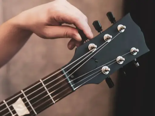 Dłoń kręci kluczem, strojąc gitarę. Słychać czysty dźwięk e, gotowy do gry.