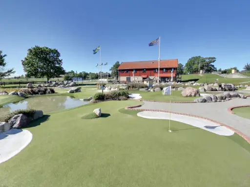 En solig dag på slussen minigolf i Sverige. Grönskande banor, vattenhål och stenar skapar en utmanande och rolig miljö.