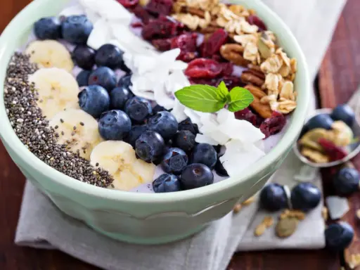 Miseczka pełna super foods: jagody, banany, nasiona chia, płatki kokosa, żurawina i granola. Idealne śniadanie.