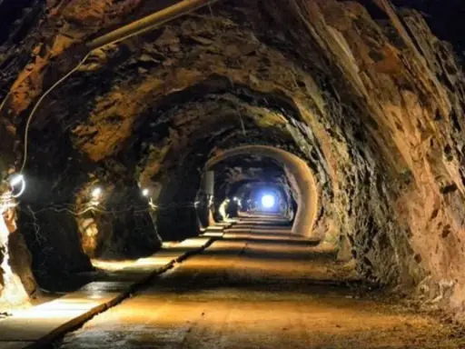 Wąski tunel w kopalni, oświetlony lampami, prowadzi w głąb ziemi. To jedne z wielu tajemniczych jaskiń Dolnego Śląska.
