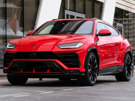 Un imponente Lamborghini Urus rojo, listo para la acción, con su diseño agresivo y llantas negras.