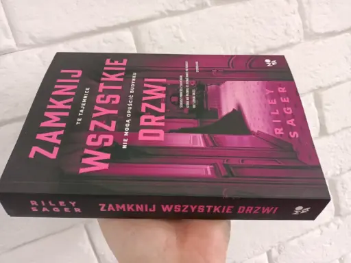 Okładka książki "Zamknij wszystkie drzwi" z różowymi neonowymi literami na czarnym tle.