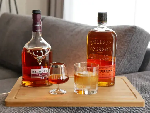 Zwei Flaschen Whiskey, Dalmore und Bulleit Bourbon, und zwei Gläser zeigen die whiskey unterschiede.