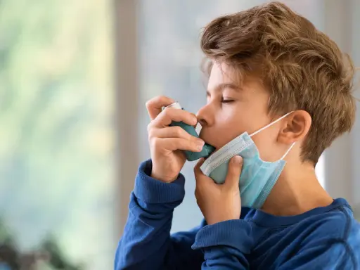 Junge mit Inhalator und Maske. Gute Behandlung beeinflusst die asthma lebenserwartung positiv.