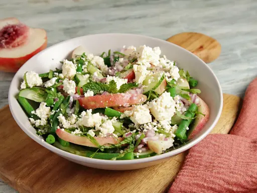Erfrischender Salat mit Nektarinenstücken, grünen Bohnen, Gurke, roten Zwiebeln und zerbröseltem Feta.