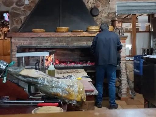 Un hombre trabaja en la cocina del restaurante Emilio Riopar, cerca de un jamonero y un horno de leña.