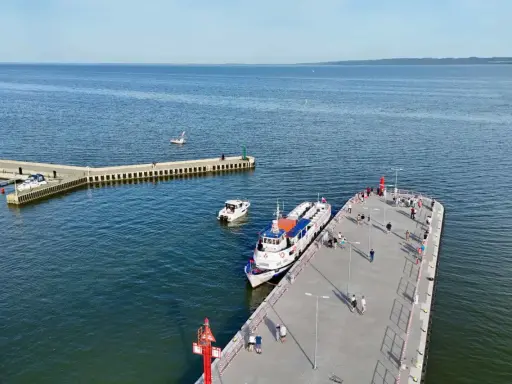 Ludzie czekają na rejsy z Krynicy Morskiej. Statek "Anita" zacumowany przy molo, obok mniejsze łodzie.